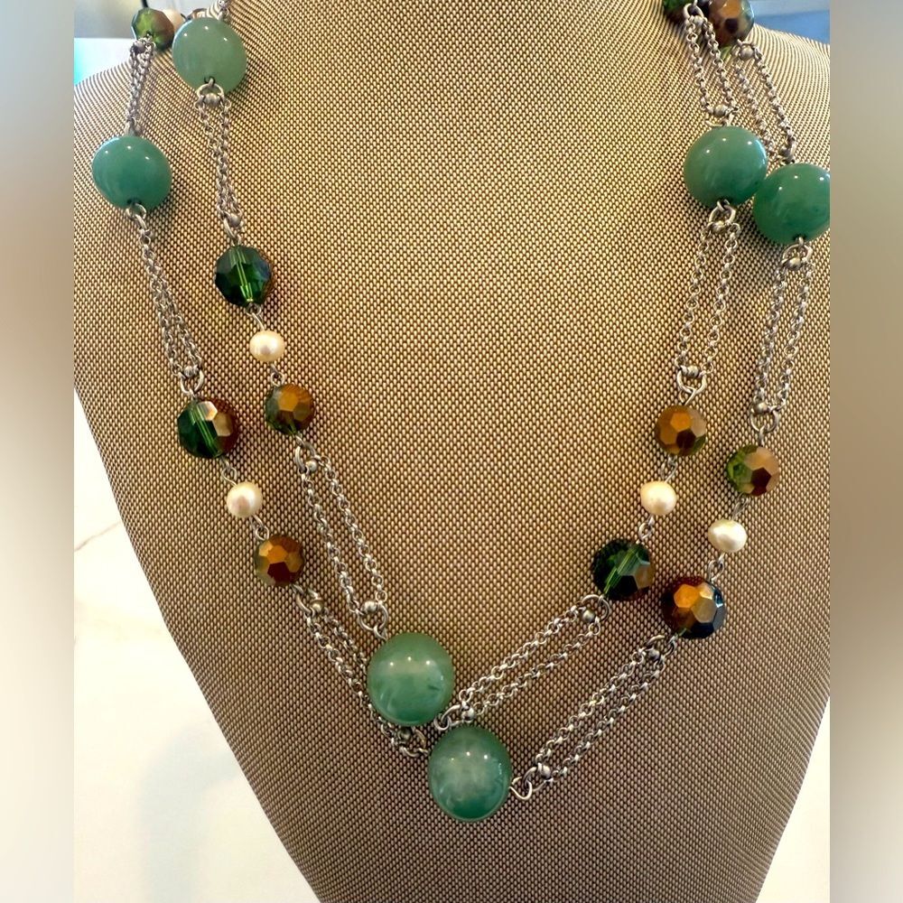 A long silver necklace featuring clusters of natural jade stone green color